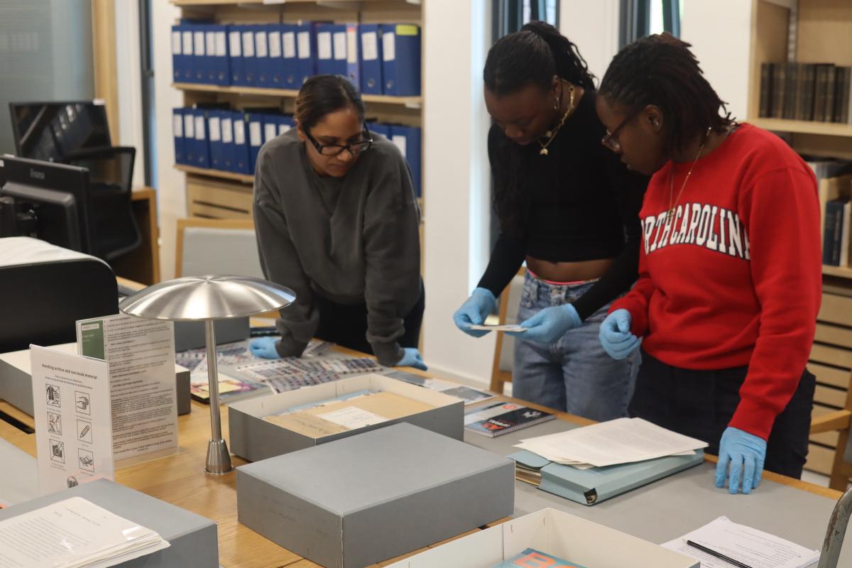 Three graduate students carefully examining archival documents together