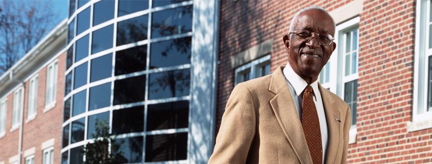 A man smiles in front of a building