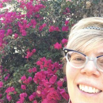 Sharon smiles in front of flowers