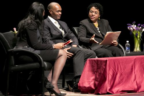 three people sitting on stage during a panel on the AME church in Charleston