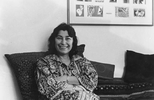 Rosetta Reitz smiling, sitting on sofa in printed dress