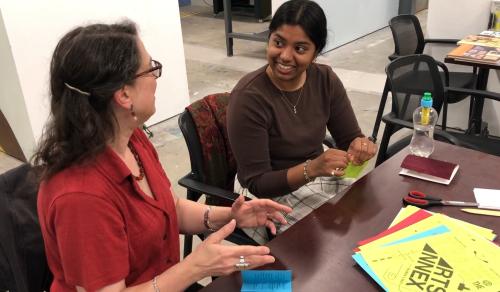 Sylvia Miller teaching workshop participant how to fold a zine